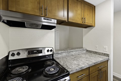 a kitchen with a stove and a counter top and wooden cabinets